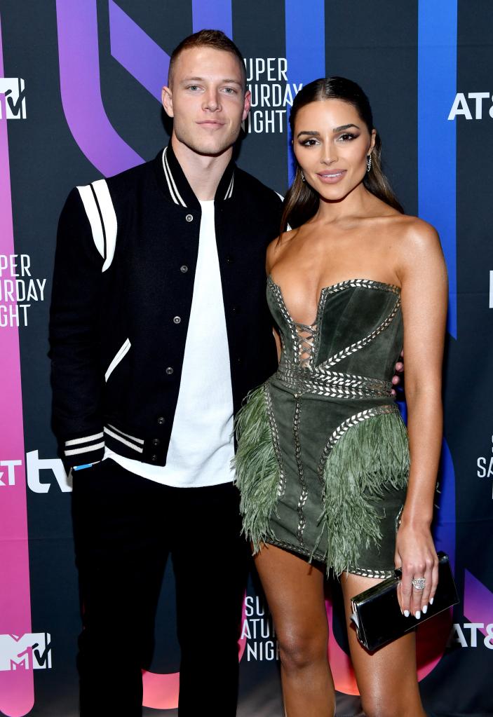 Olivia Culpo and Christian McCaffrey posing on a red carpet together.