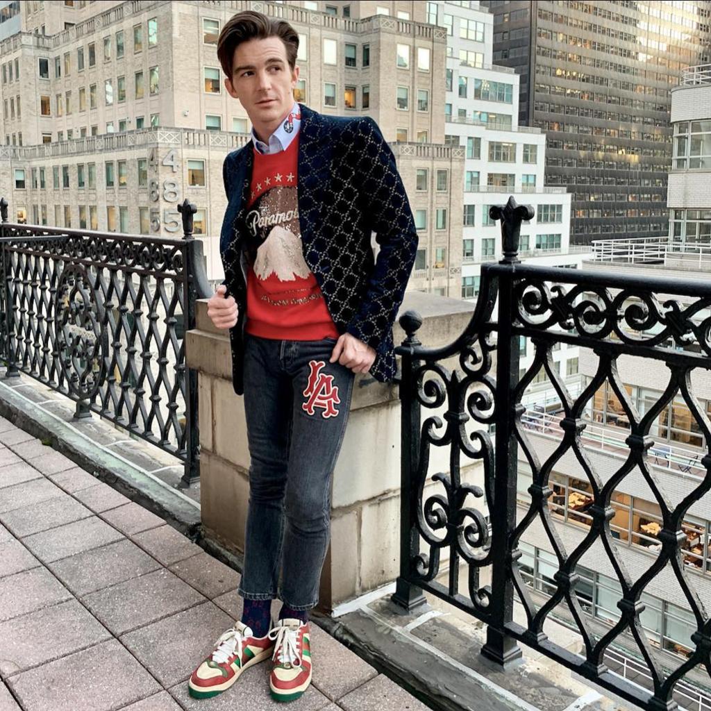 Drake Bell posing in front of a balcony.