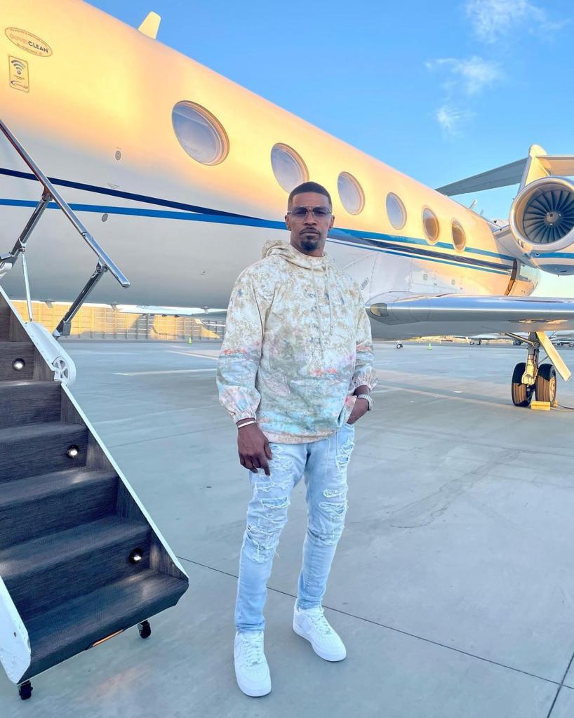 Jamie Foxx standing in front of a private plane.