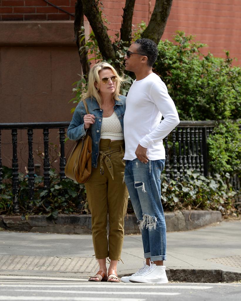 amy robach and t.j. holmes holding hands on a street corner