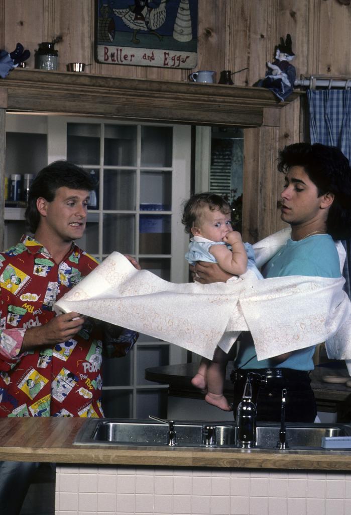 Dave Coulier and John Stamos holding one of the Olsen twins for "Full House."