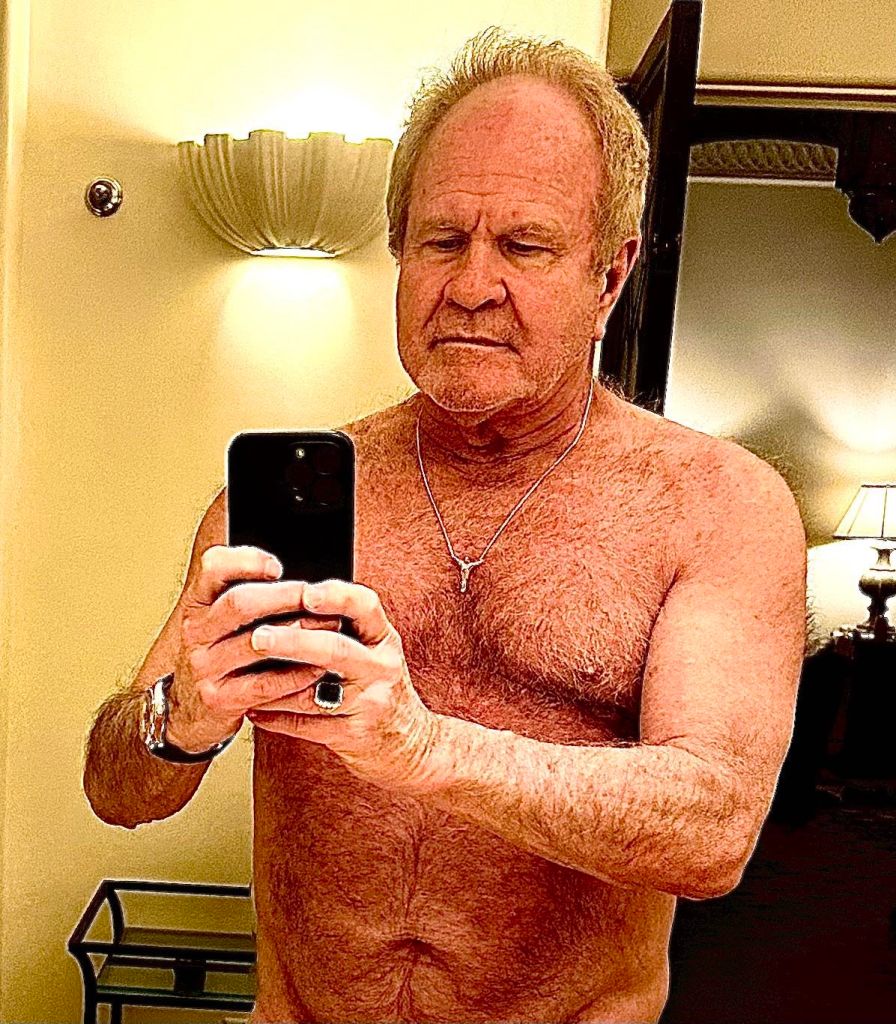 Jim Wilkes taking a shirtless selfie in a mirror.