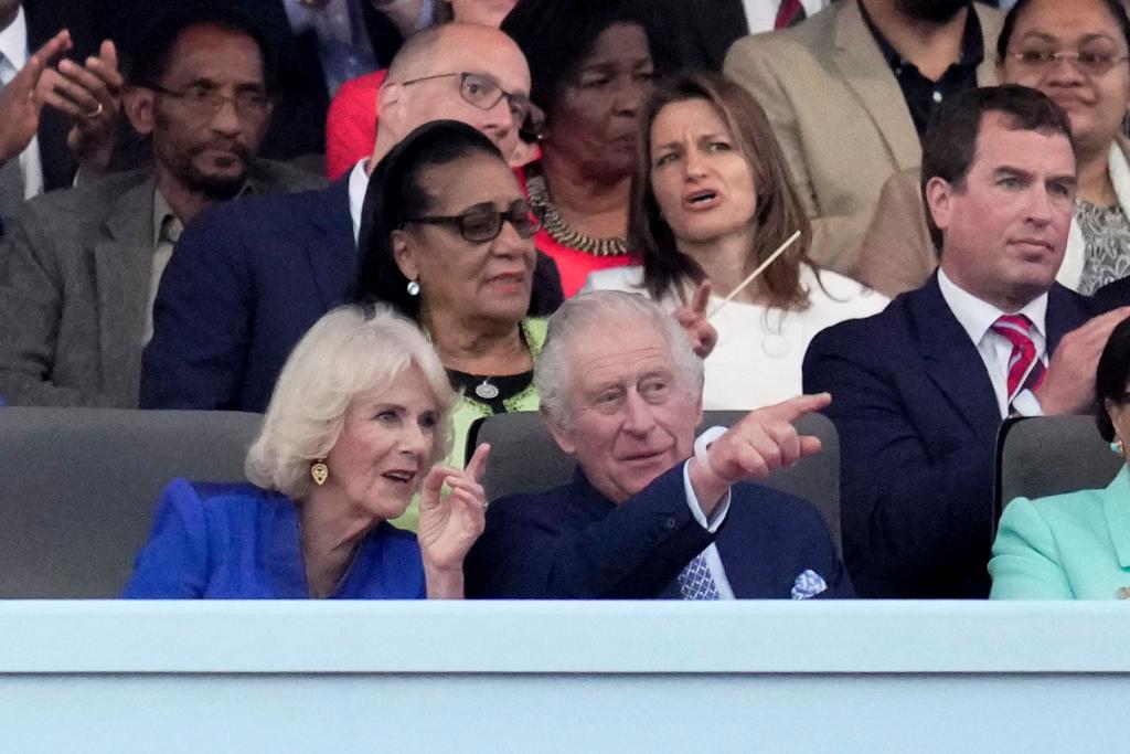 Queen Camilla and King Charles III pointing while watching the coronation concert.