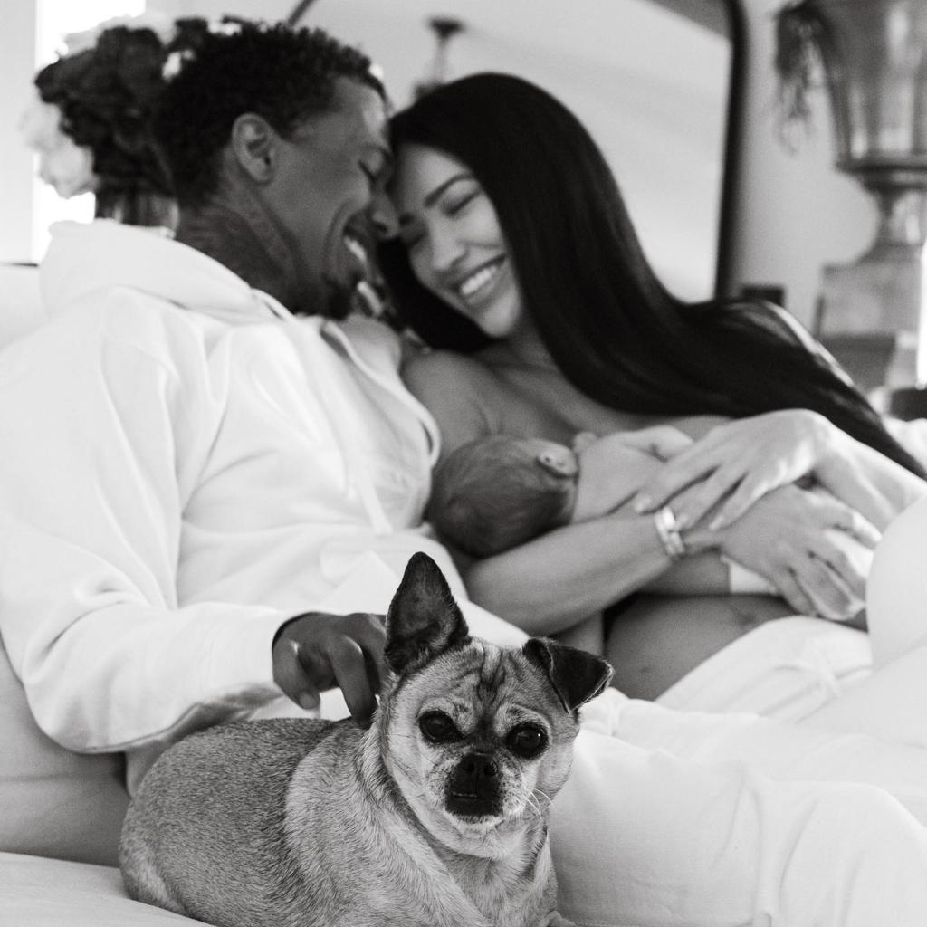 Bre Tiesi and Nick Cannon posing with their baby and their dog.