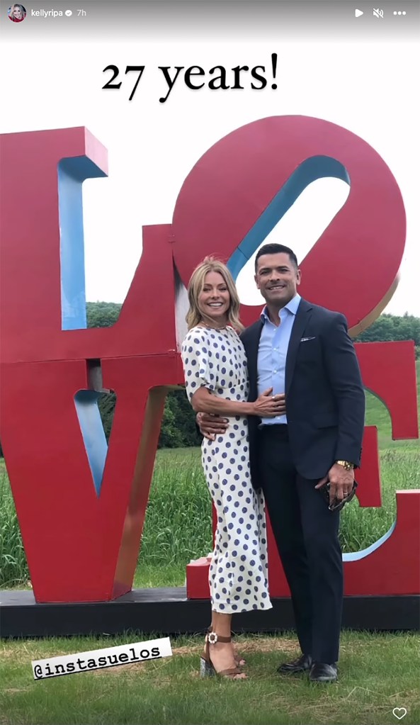 Kelly Ripa and Mark Consuelos in front of a "Love" sculpture. 