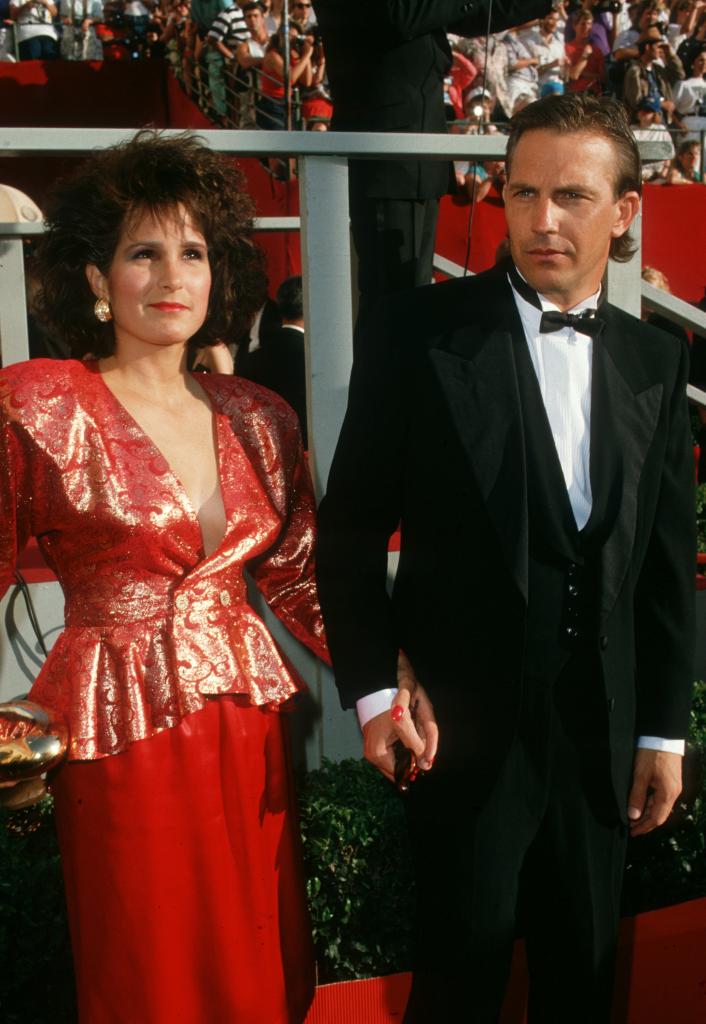 Kevin Costner and Cindy Silva holding hands while at an event.