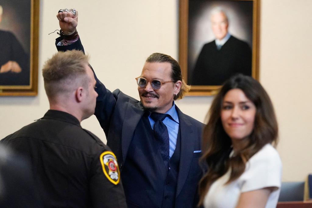 Johnny Depp pumping his fist in the air in court with his lawyer by his side.