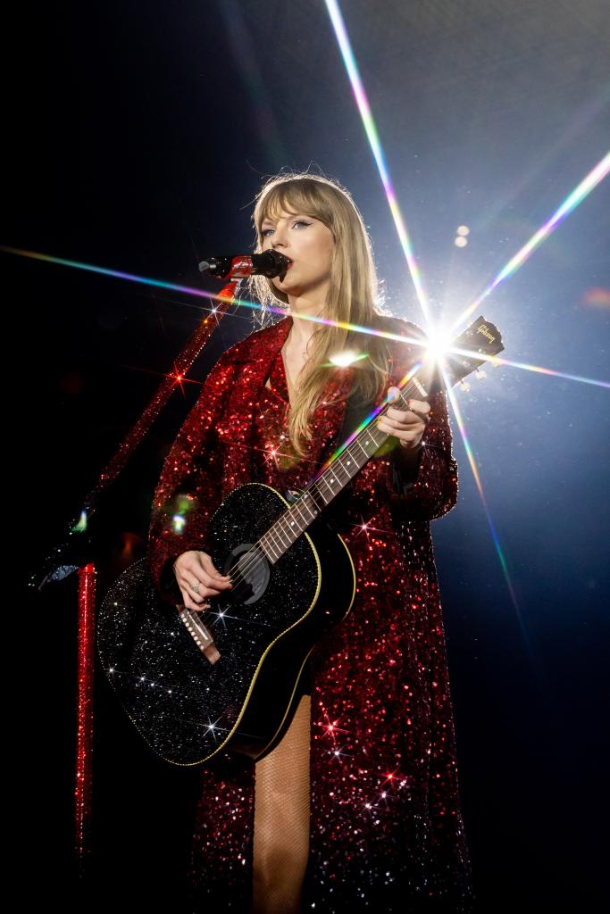 Taylor Swift playing guitar onstage.