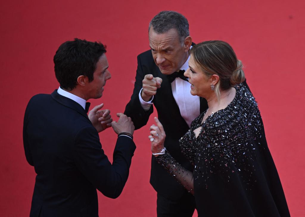 terse-looking tom hanks and rita wilson talking to a man