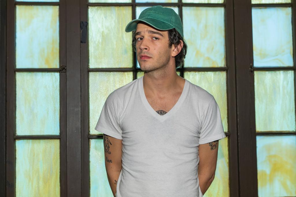 Matty Healy wears baseball cap, white tee