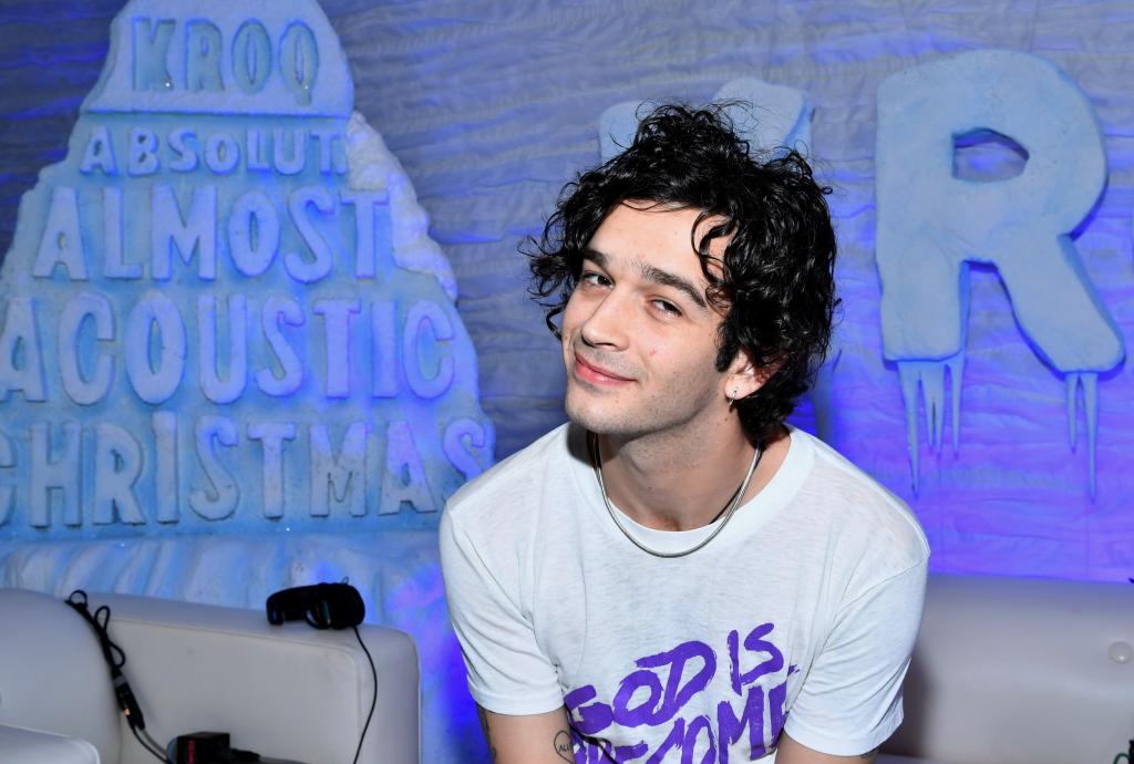 Matty Healy sits in white tee