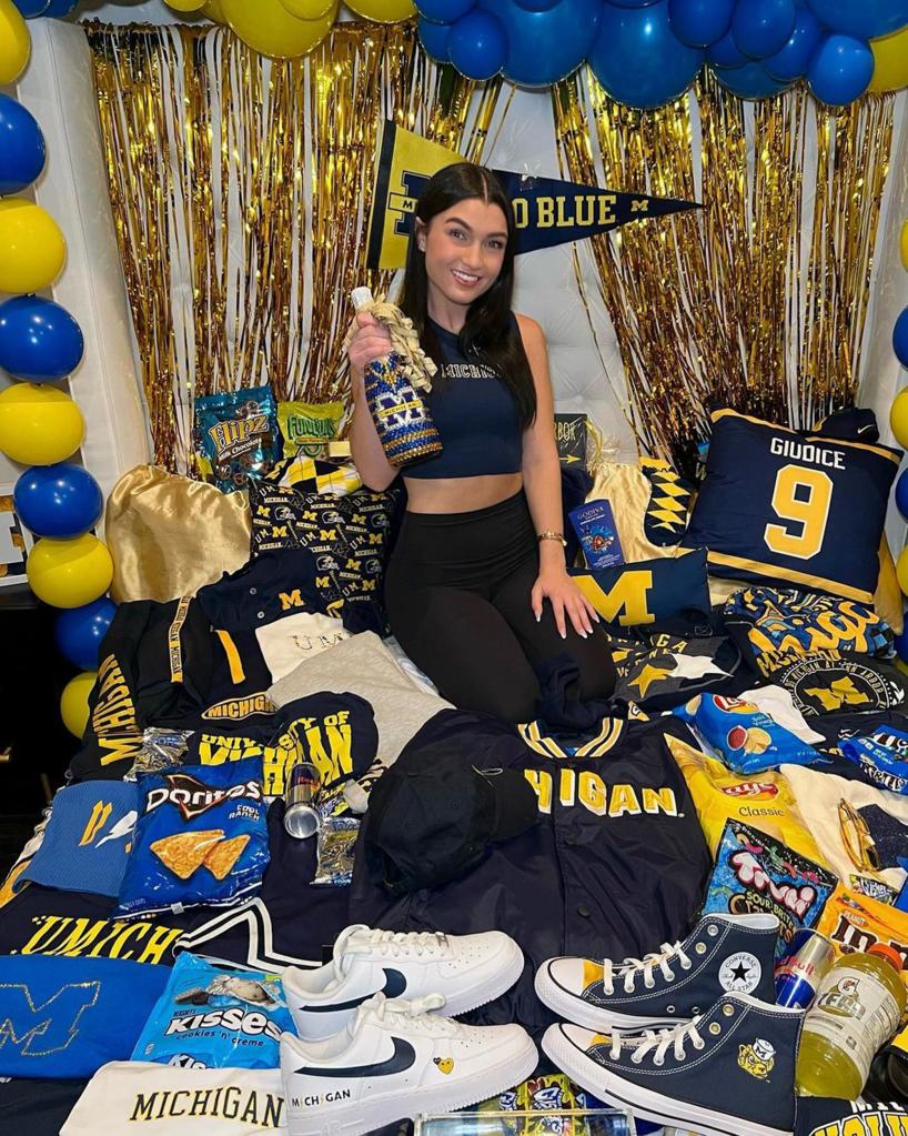 Gabriella Giudice sitting on a bed with University of Michigan gear on it