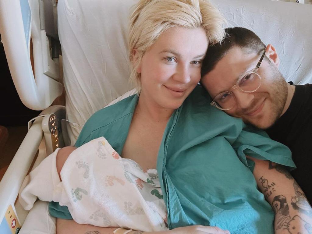 Ireland Baldwin and RAC laying in bed with their baby.