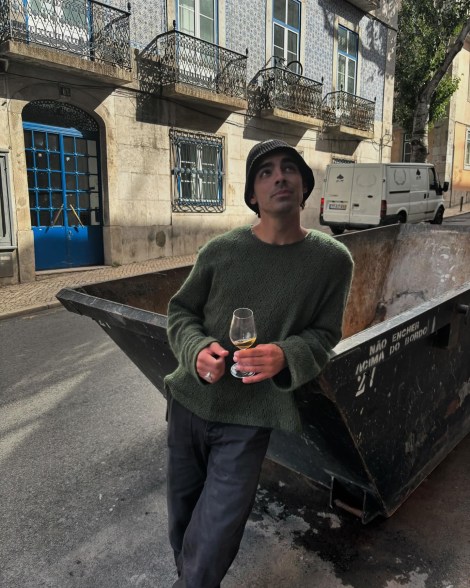 Joe Jonas drinks wine on the street in Portugal.