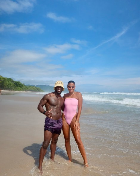 Kevin and Eniko Hart take a photo on a beach.