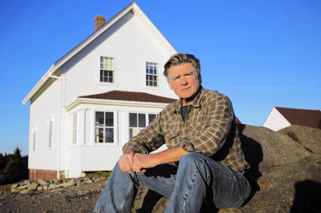 Treat Williams sitting in front of house