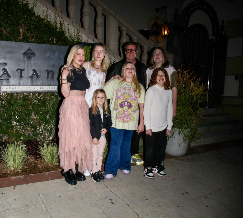 Tori Spelling and Dean McDermott posing with their kids in front of a house.