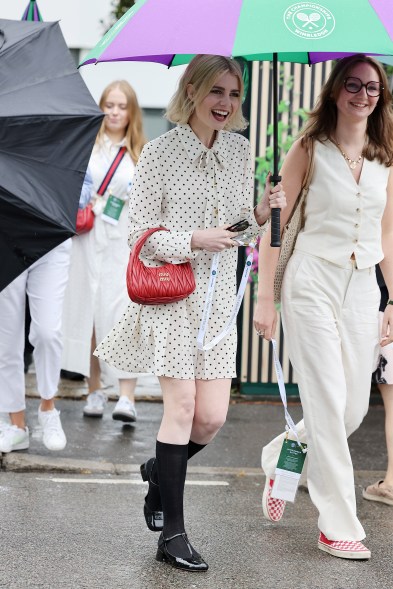 Lucy Boynton walking under an umbrella