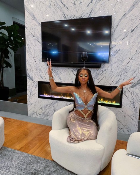 saweetie looking zen with her arms stretched out sitting on a chair