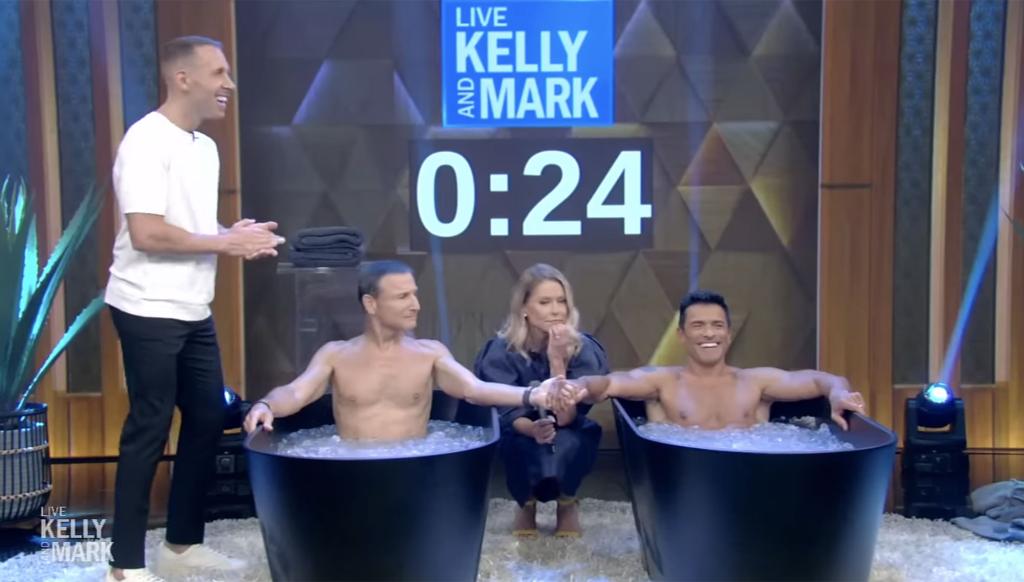 Mark Consuelos sitting in an ice tub with Kelly Ripa standing behind him