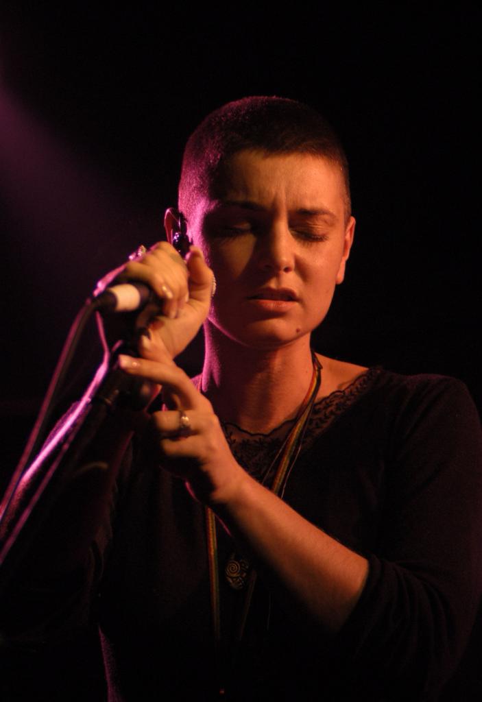 Sinéad O'Connor singing into a microphone.