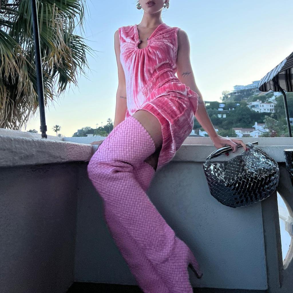 dua lipa sitting on a balcony in barbie pink and thigh-high boots