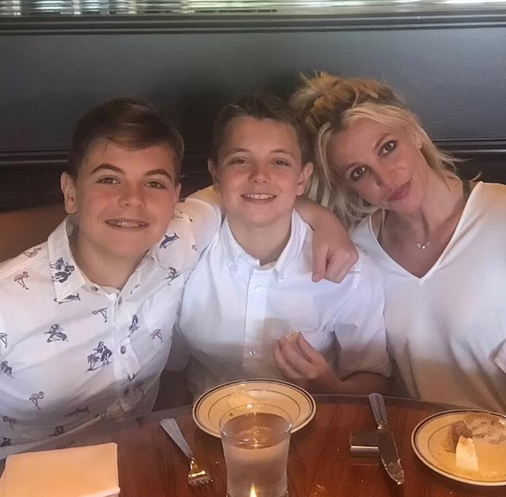 Britney Spears posing with her sons in a restaurant booth.
