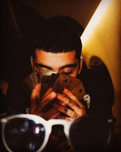 zayn malik hiding his face behind a deck of cards