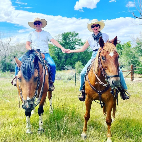Elizabeth Banks and her husband, Max Handelman, hold hands while horseback riding.