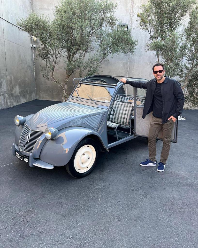 Alex Manos posing by a car