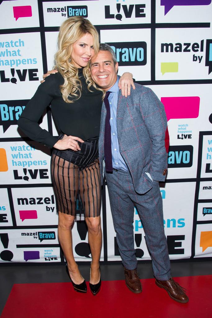 Full length shot of Brandi Glanville, in sheer skirt, and Andy Cohen embracing with "What What Happen Live" backdrop. 