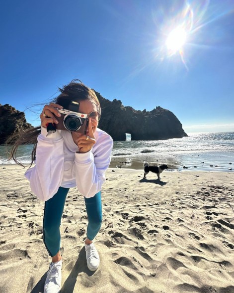 Nina Dobrev holding a camera to her eye on the beach