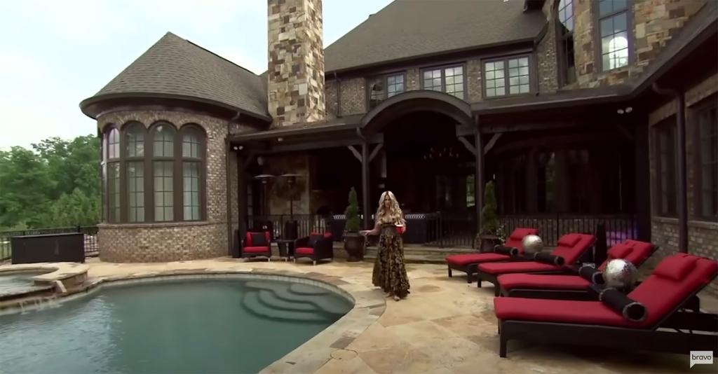 kim zolciak posing by her house's pool and chaise lounge chairs