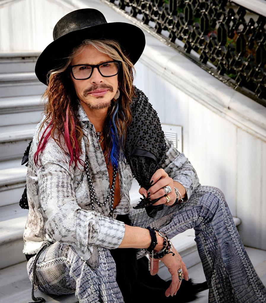 Steven Tyler sitting on stairs.