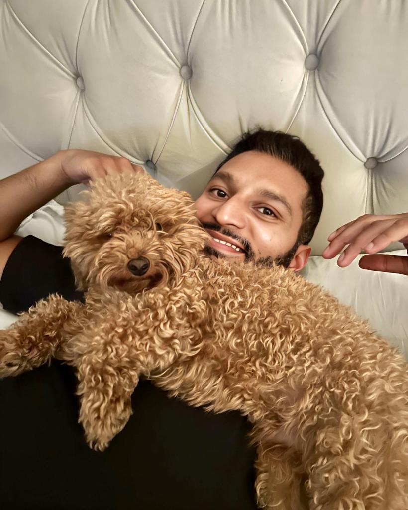 Shake Chatterjee in bed with a puppy over him.