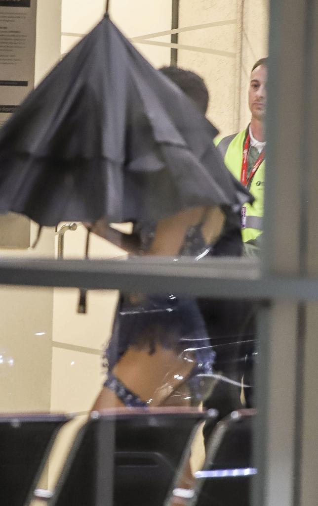 Taylor swift at the airport under an umbrella. 