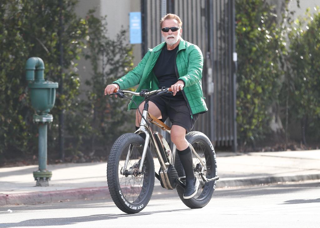 Arnold Schwarzenegger riding a bike.