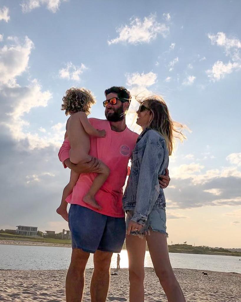 tim rosenman holding his naked son while posing on the sand with his wife, whitney port