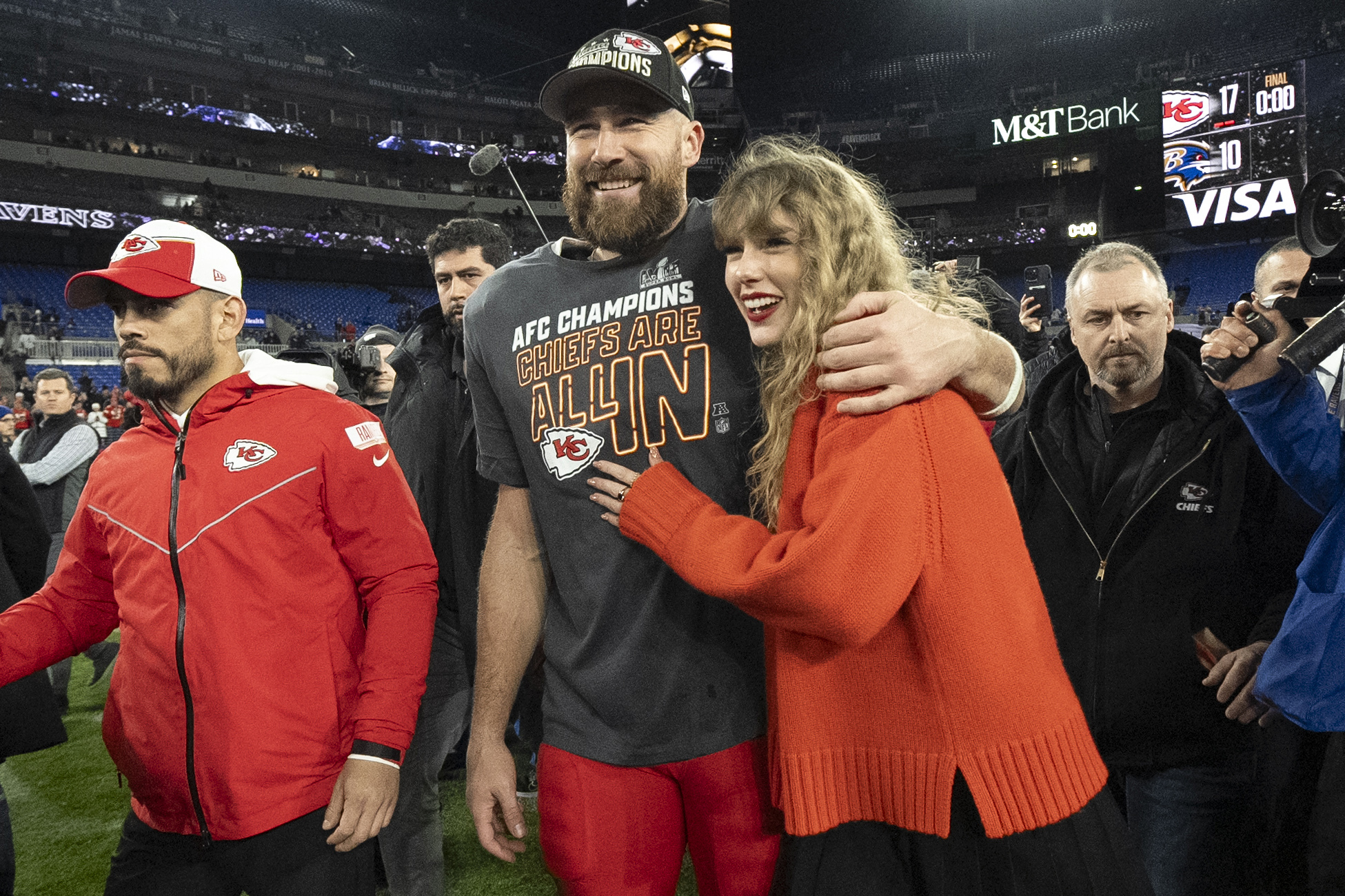 Taylor Swift hugging Travis Kelce on a football field.