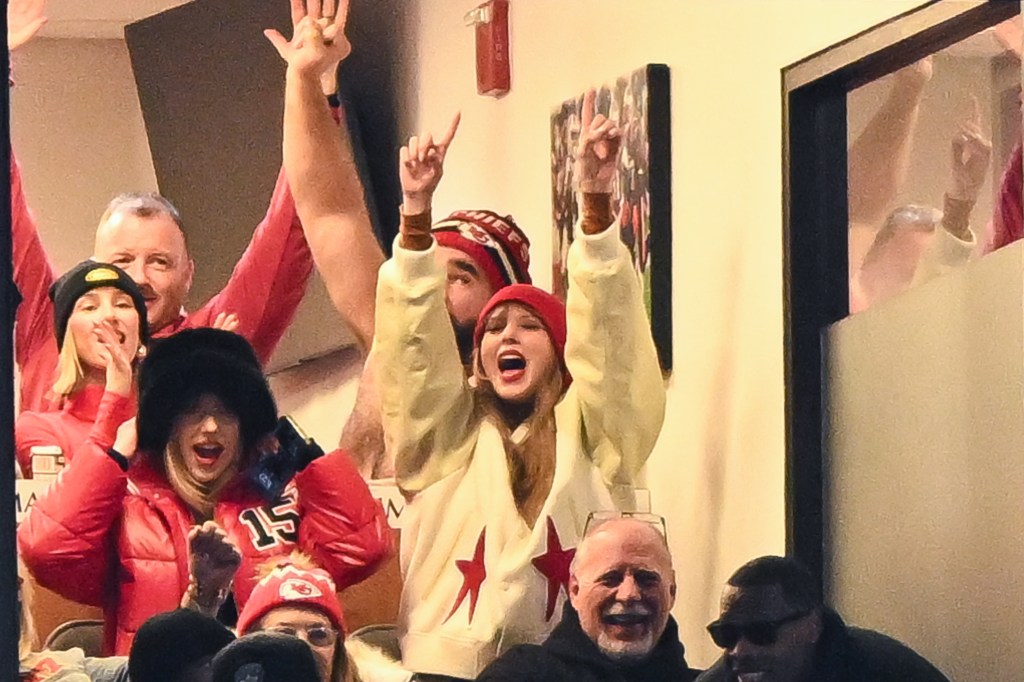 brittany mahomes and taylor swift cheering with her arms raised