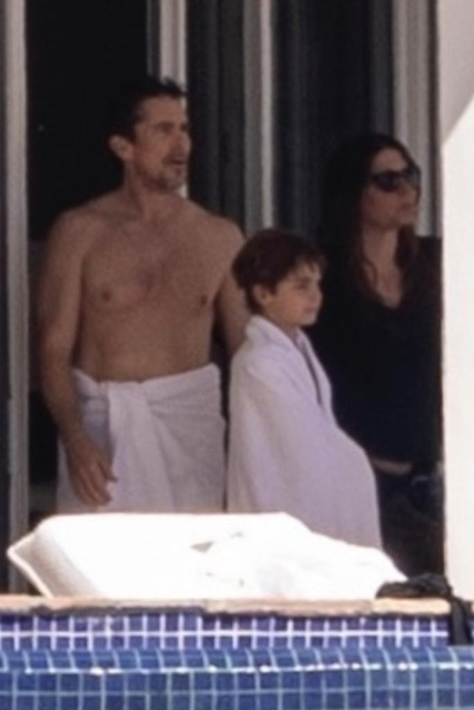 Christian Bale with a towel around his waist with his son.
