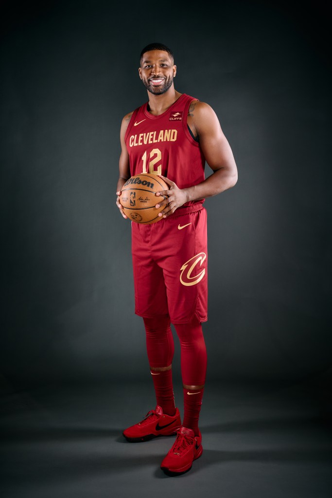 tristan thompson holding a basketball and posing in his Cleveland Cavs red jersey