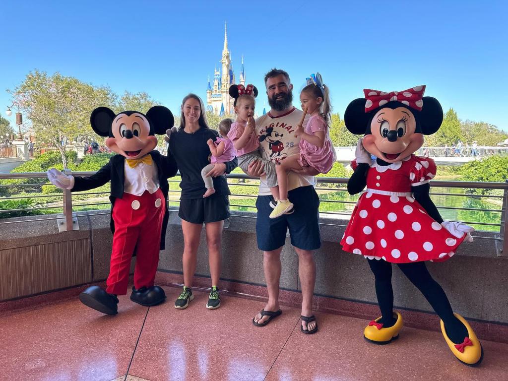 jason and kylie kelce posing with mickey and minnie mouse and their three daughters