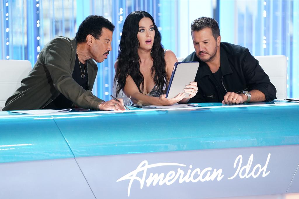 lionel richie and luke bryan looking over at a tablet that katy perry is holding