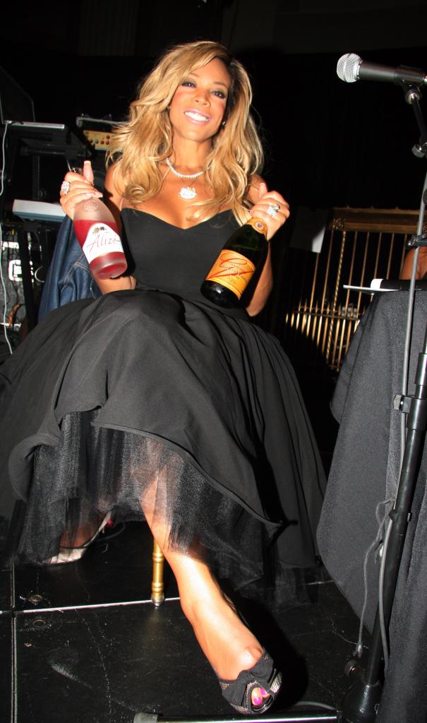 Wendy Williams holding two bottles of alcohol.