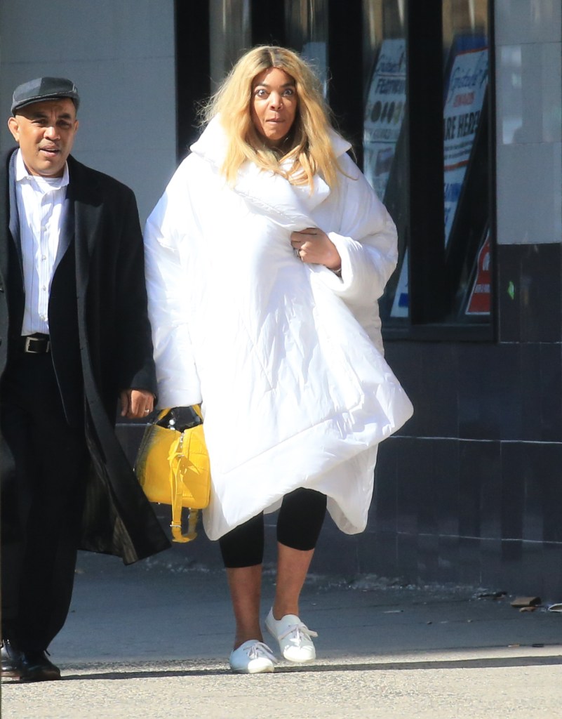 Wendy Williams walking while wearing a big white coat.