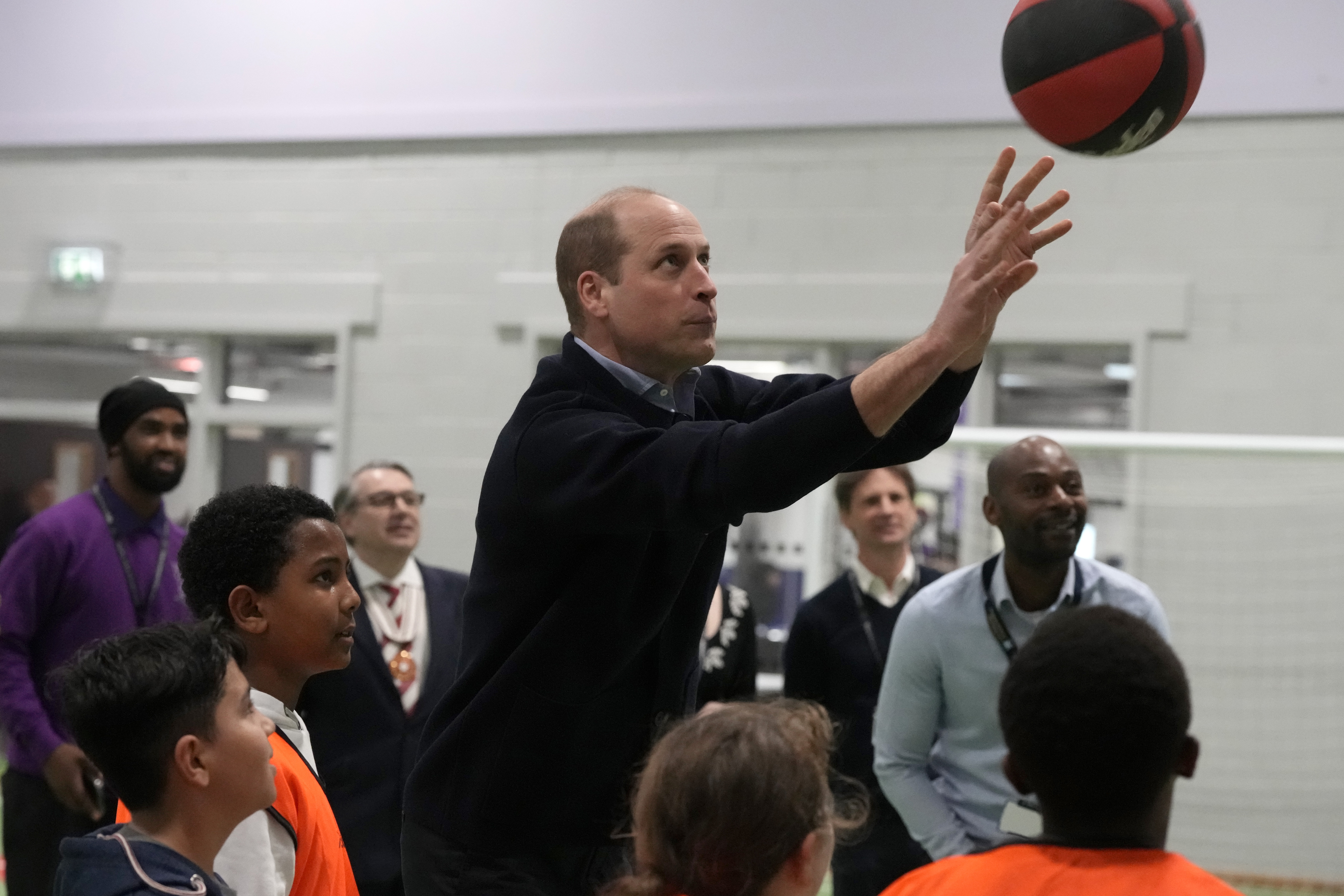 prince william shooting a basket surrounded by kids