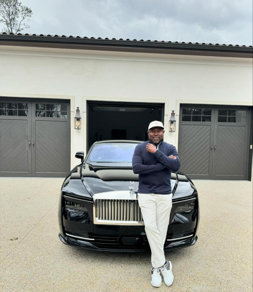 Simon Guobadia posing in front of a Rolls-Royce