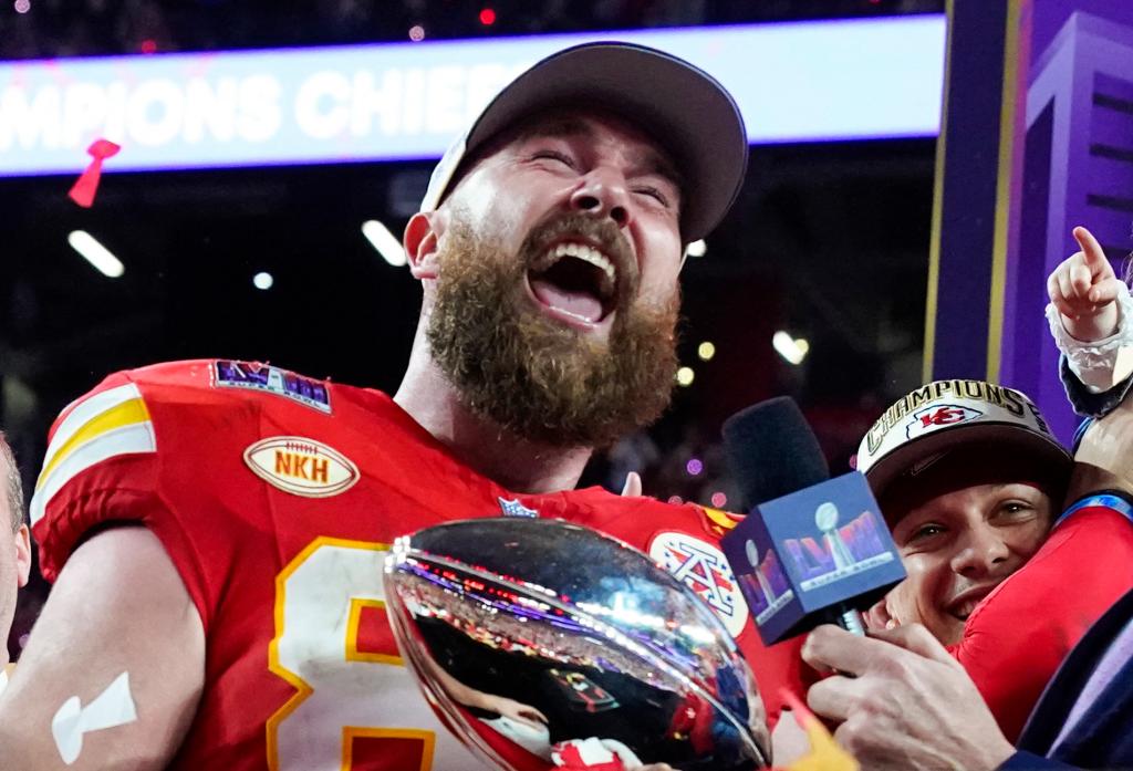 Travis Kelce holding a Super Bowl trophy. 