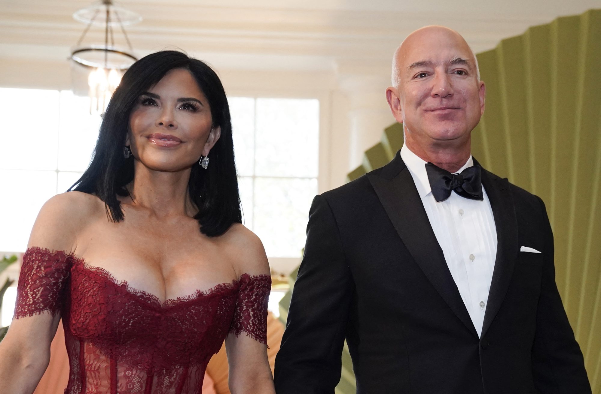 Jeff Bezos and Lauren Sanchez smile as they arrive at the White House.